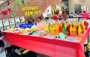 Display table during Hispanic Heritage month with red tablecloth and Jalisco sodas