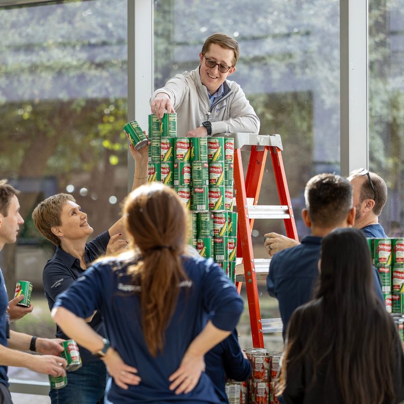 GE Aerospace employees work with TCC students at TCC Trinity River to build structures out of donated canned food.